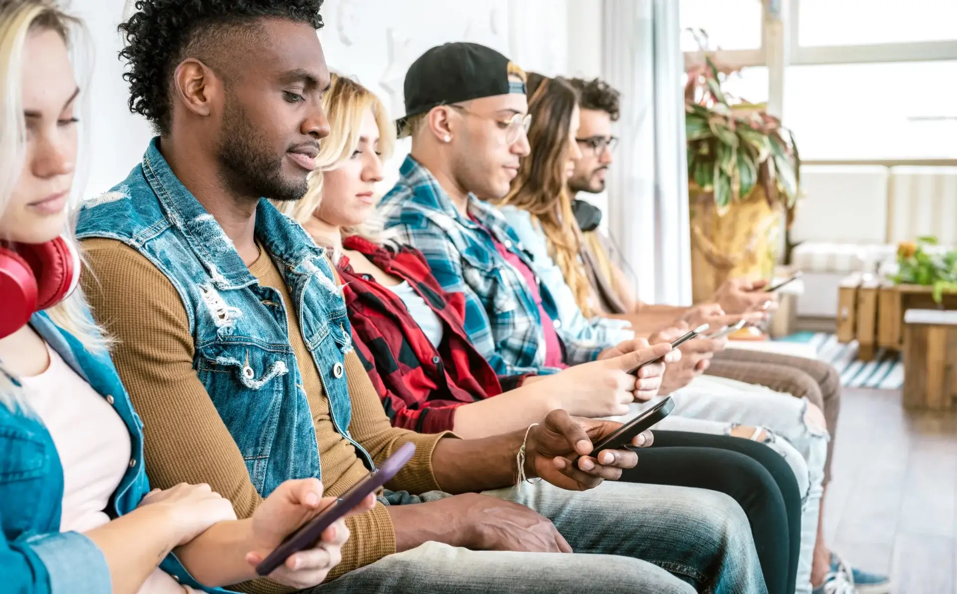 Row of Young Adults looking at their Phones