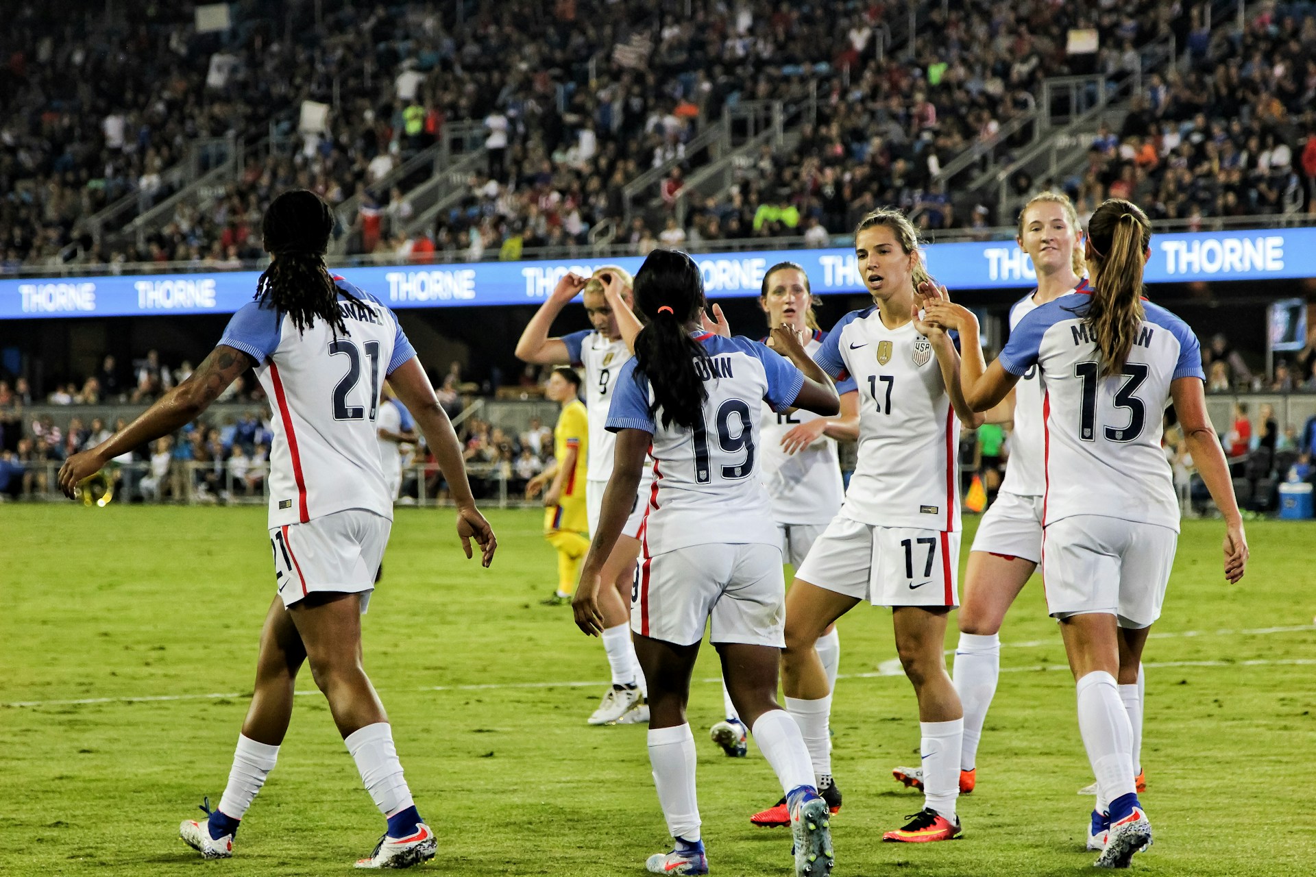 Women's football team celebrating a goal in a packed stadium